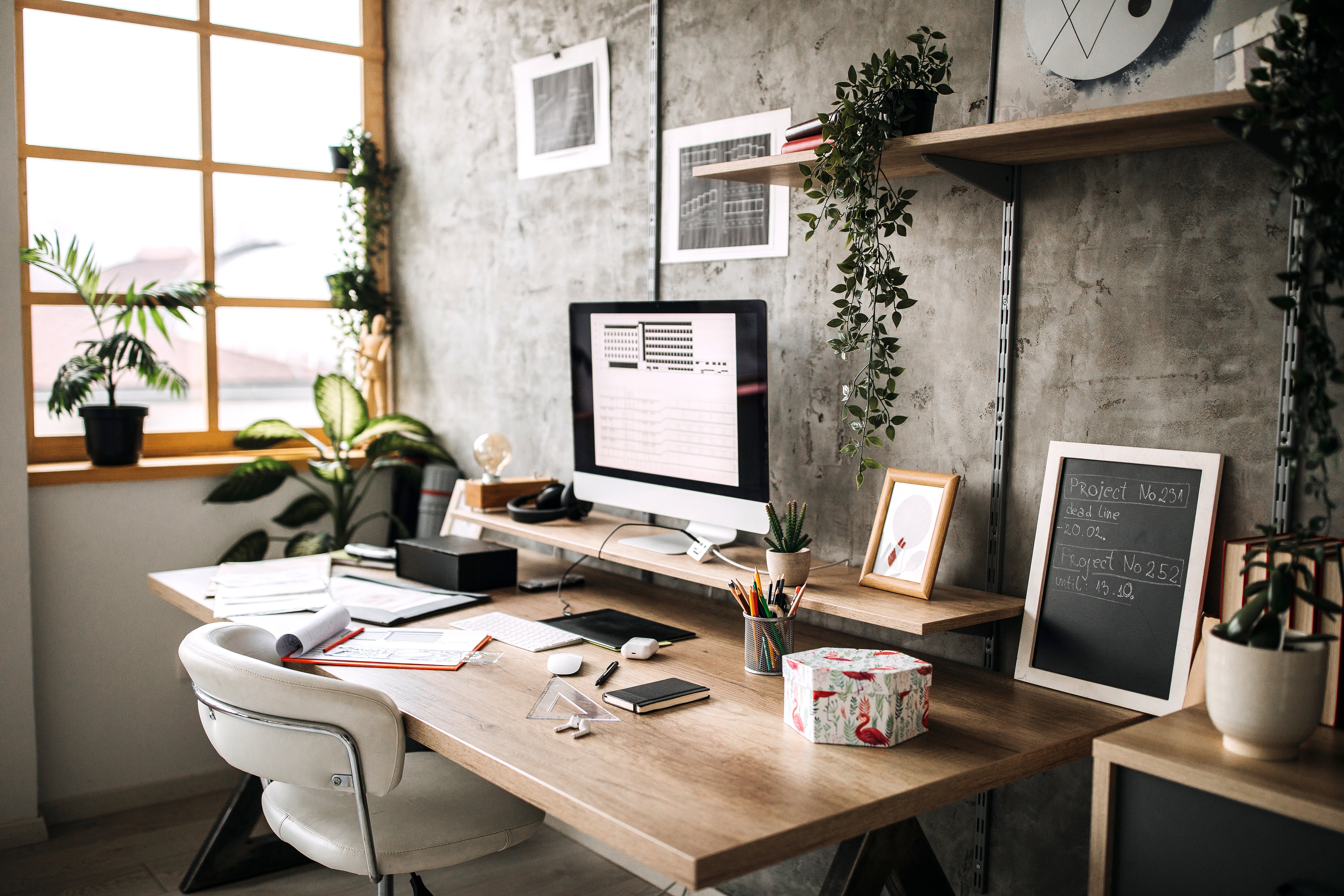 Home office with desk next to a large window facing a concrete wall